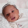 Annalee is registered to the contest to win money with this photo: baby, infant, face, headband, flower, white_clothing, blanket, close_up, portrait, cute, newborn, soft_lighting, indoors, child, young, expression, smile, skin, person, resting