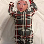 Ayden is registered to the contest to win money with this photo: baby, blanket, child, christmas, cozy, cute, expression, face, festive, headwear, holiday, indoors, infant, lying_down, onesie, plaid, santa_hat, soft, warm, wide_eyes