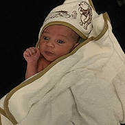 Roshaantè is registered to the contest to win money with this photo: baby, blanket, bodypart, bonnet, cap, clothing, face, finger, hand, hat, head, hood, hoodie, knitwear, newborn, person, photography, portrait, quilt, towel