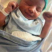 Xayvièn joined the competition — help win amazing prizes! newborn, baby, infant, smile, hat, knitted_hat, blanket, blue_blanket, clothing, bed, sleeping, face, hand, wristband, cute, cozy, indoors, person, rest, peaceful