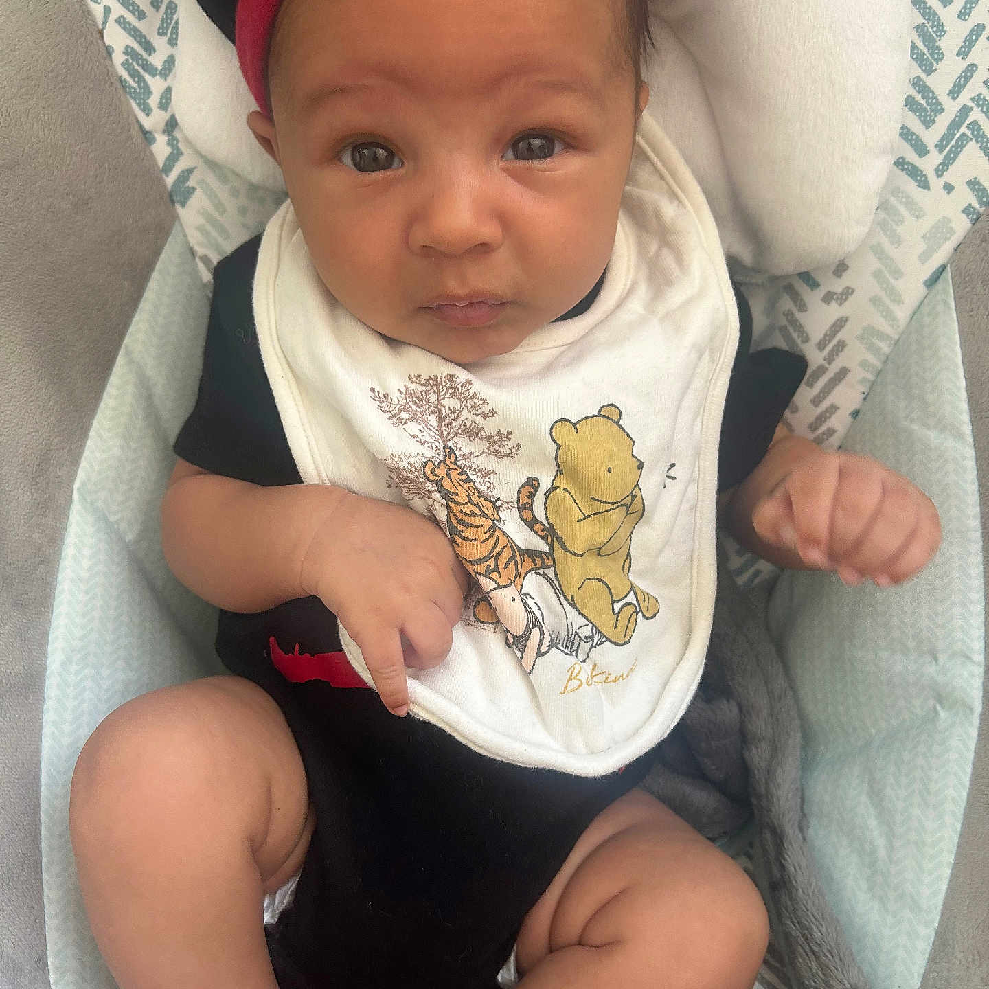 Xayvièn is registered to the contest to win money with this photo: baby, bib, black_clothing, blanket, child, closeup, comfort, cushion, cute, expression, face, headwear, indoors, infant, looking, red_hat, seated, socks, soft_texture, winnie_the_pooh