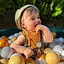 toddler, child, ball_pit, hat, bib, plastic_balls, outdoor, happy, smiling, sunlight, greenery, play, cute, baby, portrait, cheerful, summer, fun, closeup, colorful