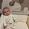 baby, infant, four_months, pajamas, elephant_pattern, blanket, embroidered_name, cozy_chair, cream_color, cute, sitting, portrait, indoors, soft_texture, child, smiling, feet, hand, comfort, warm