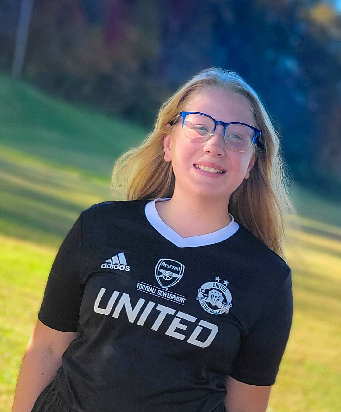 Coraline is registered to the contest to win money with this photo: active_shirt, blond, brown_hair, electric_blue, eyewear, flash_photography, fun, glasses, grass, grassland, happy, joy, landscape, leisure, long_hair, people_in_nature, person, recreation, sleeve, smile