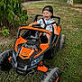 toddler, child, toy_car, outdoor, grass, trees, cap, smiling, playful, happy, nature, vehicle, fun, summer, greenery, young_child, recreation, daytime, expression, casual_clothing