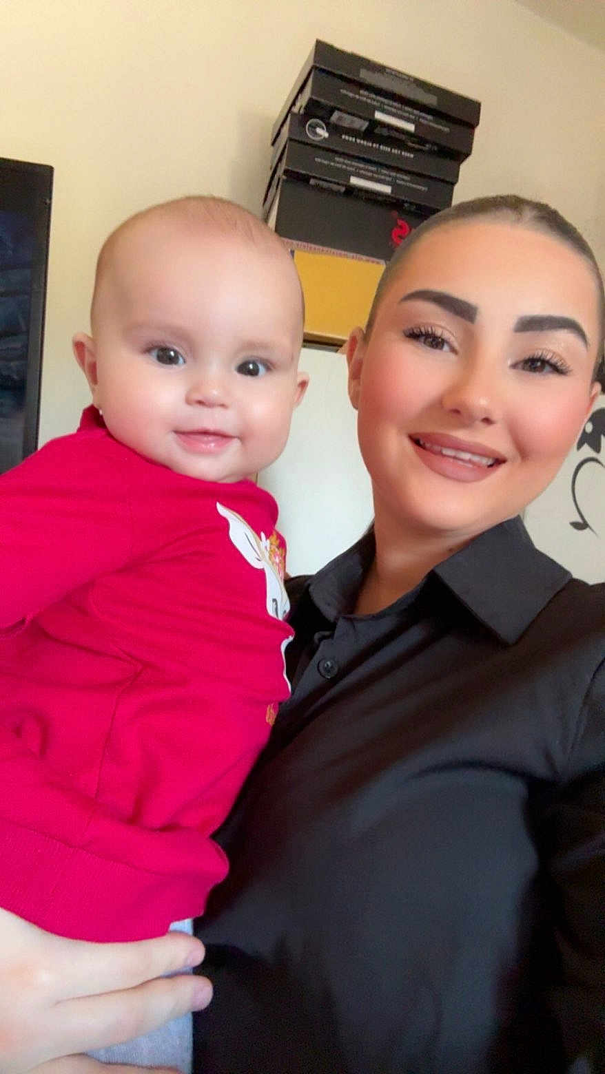 Kataleya a rejoint le concours — aidez-le/la à gagner de superbes lots ! baby, infant, woman, adult, person, smiling, portrait, selfie, indoor, red_shirt, black_shirt, holding, face, eyes, eyebrows, hand, boxes, stacked_boxes, makeup, cute