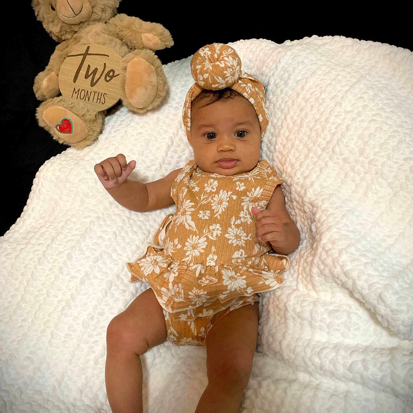 Sophia joined the competition — help win amazing prizes! baby, blanket, celebration, child, comfort, cute, floral_pattern, headband, indoor, infant, lying_down, milestone, newborn, person, portrait, romper, smiling, soft_texture, teddy_bear, toy