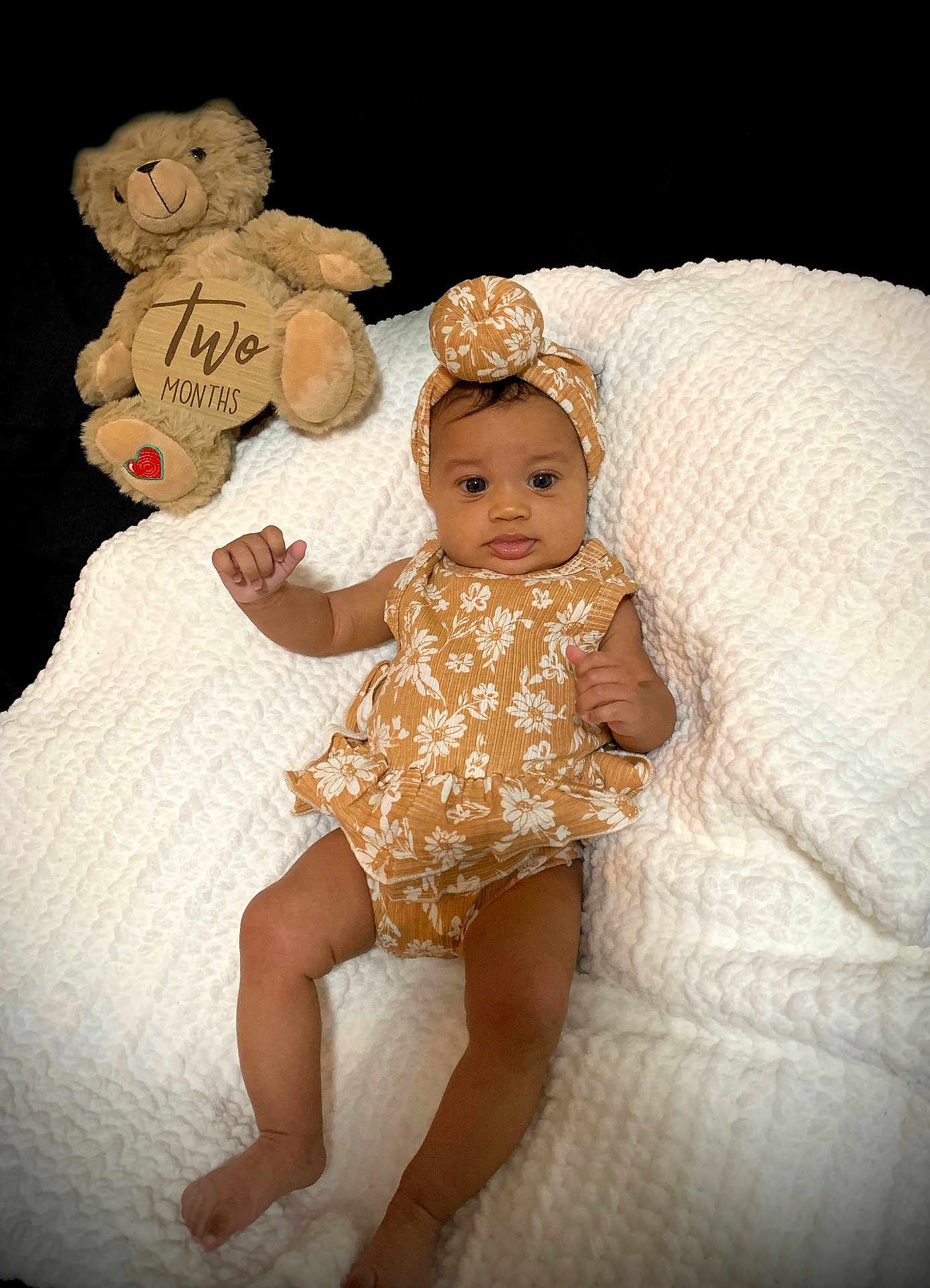 Sophia joined the competition — help win amazing prizes! baby, infant, teddy_bear, blanket, headband, romper, milestone, cute, portrait, soft_texture, floral_pattern, child, smiling, lying_down, indoor, toy, comfort, newborn, celebration, person