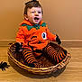 baby, basket, clothing, coat, cutlery, face, glove, happy, hardwood, head, jacket, laughing, pants, person, photography, plant, portrait, pottedplant, sitting, wood