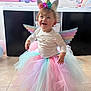 celebration, child, colorful, costume, cute, decor, floor, happy, headband, indoor, party, pastel_colors, person, playful, smiling, tile, toddler, tutu, unicorn, wings