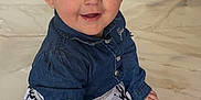 Lola participe au concours pour gagner de l'argent avec cette photo : toddler, child, smiling, denim_jacket, dress, patterned_clothing, floor, marble_floor, sitting, happy, cute, face, portrait, indoor, young_child, small_hands, long_sleeves, buttoned_jacket, eyes, hair