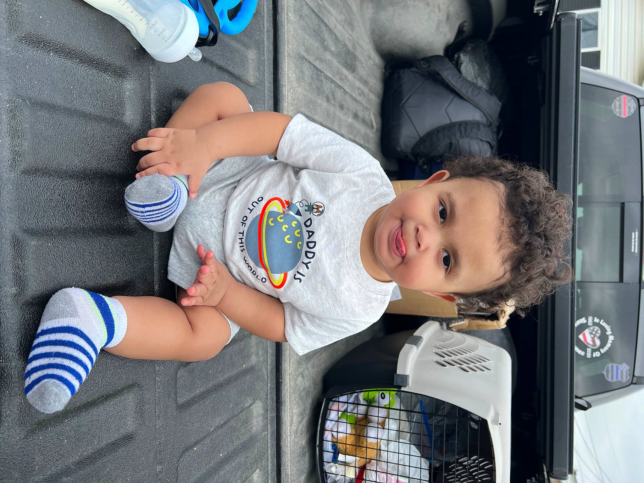 Greyson is registered to the contest to win money with this photo: auto_part, automotive_design, automotive_exterior, baby, baby_products, baby_toddler_clothing, blue, child, hat, human_leg, knee, motor_vehicle, person, smile, sneakers, t_shirt, thigh, toddler, travel, vehicle