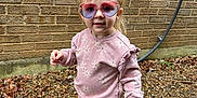 Oakleigh is registered to the contest to win money with this photo: child, toddler, sunglasses, heart_shaped_sunglasses, pink_outfit, floral_pattern, sneakers, gravel, brick_wall, outdoor, walking, blonde_hair, ponytail, portrait, cute, accessory, casual_clothing, small_earrings, fashion, playful
