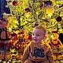 Hudson is registered to the contest to win money with this photo: baby, child, christmas_tree, ornaments, plush_toys, holiday, festive, lights, smiling, indoors, winter_clothing, sitting, cozy, decorations, toy_snowmen, blanket, cute, happy, face, portrait