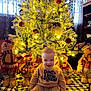 baby, child, infant, christmas_tree, christmas_lights, ornaments, plush_toy, snowman, holiday, smile, sitting, onesie, tree_skirt, cozy, warm_lighting, festive, curtains, home_interior, decorations, floor