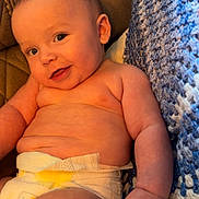 Hudson joined the competition — help win amazing prizes! baby, infant, diaper, smiling, cute, chubby, skin, hand, face, blue_blanket, knitted, couch, comfort, indoors, portrait, child, young, happy, relaxed, cozy