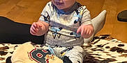 Hudson is registered to the contest to win money with this photo: baby, child, pajamas, blanket, floor, smile, indoor, wood_floor, sweater, sock, person, face, cute, happy, clothing, pattern, infant, toy, home, furniture