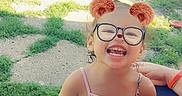 London joined the competition — help win amazing prizes! child, girl, smiling, glasses, outdoor, portrait, happy, laughing, sitting, grass, backyard, sunlight, summer, playful, digital_filter, bear_ears, pink_clothing, family, pavement, casual_photo