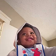 Matthew joined the competition — help win amazing prizes! baby, child, hoodie, bib, smile, indoor, happy, infant, face, clothing, person, cute, portrait, young_child, warm_clothes, expression, closeup, headwear, apparel, home