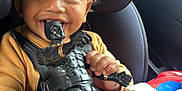 Jahqaari joined the competition — help win amazing prizes! action_figure, black_panther, car_interior, car_seat, child, clothing, curly_hair, face, hands, happy, indoor, playful, plush_toy, portrait, seatbelt, smiling, spiderman, sweater, toddler, toy