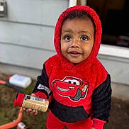 Jahqaari joined the competition — help win amazing prizes! black_clothing, casual_wear, child, close_up, curious, daylight, face, grass, holding_object, hoodie, house_wall, outdoor, person, playful, red_clothing, smiling, toddler, toy_shoes, window, young_child