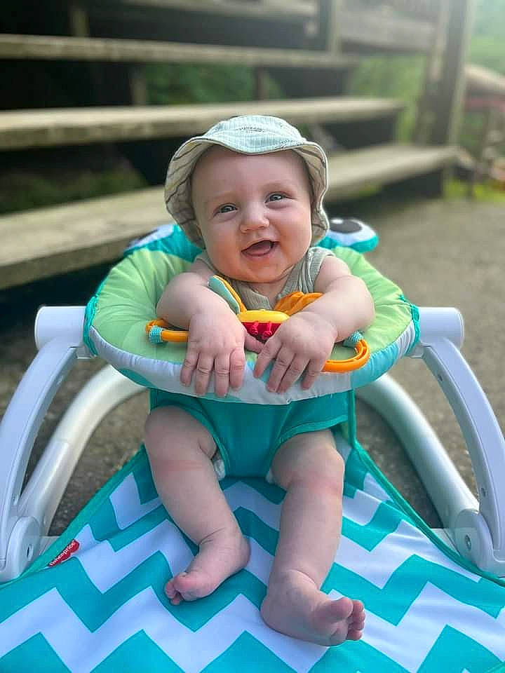 Kolby is registered to the contest to win money with this photo: baby, baby_products, baby_toddler_clothing, chair, child, comfort, face, fun, grass, happy, hat, headwear, leisure, outdoor_furniture, person, play, recreation, sitting, skin, smile
