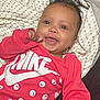 Nova is registered to the contest to win money with this photo: baby, infant, smiling, red_clothing, nike, blanket, pattern, happy, cute, face, skin, hand, lying_down, indoors, child, portrait, apparel, fabric, expression, person