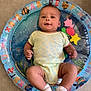 baby, infant, onesie, socks, inflatable_ring, alphabet, sea_creatures, floor, child, smiling, cute, indoor, playtime, floating, water_toy, colorful, young_child, happy, portrait, person
