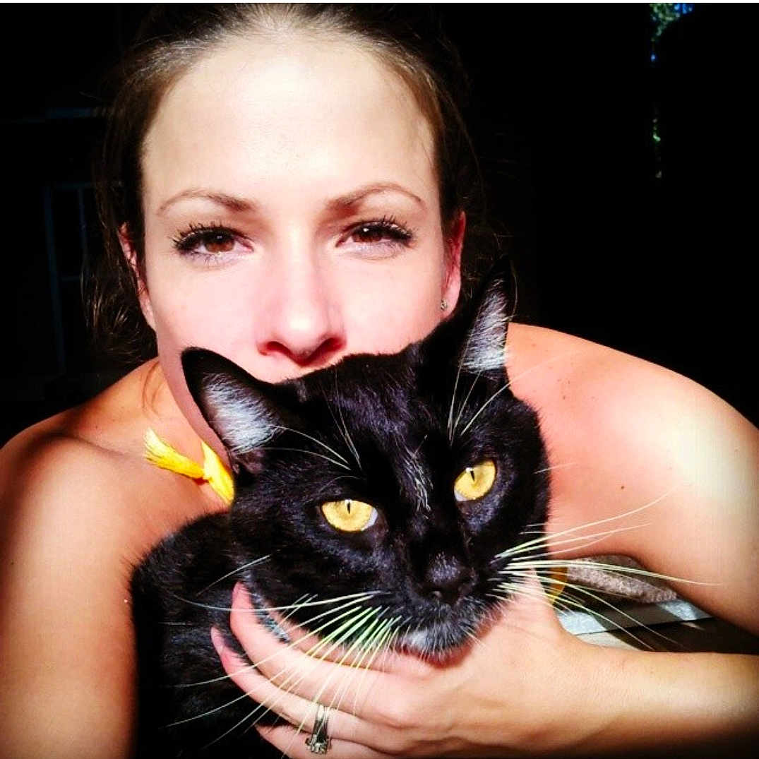 Boots is registered to the contest to win money with this photo: black_cat, black_hair, brown_hair, carnivoran, cat, cat_like_mammal, domestic_short_haired_cat, eye, face, girl, joy, lip, mammal, neck, person, small_to_medium_sized_cats, smile, whiskers