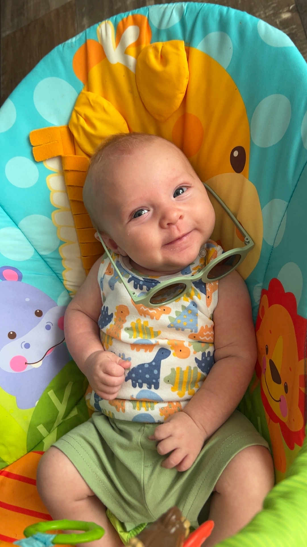 August joined the competition — help win amazing prizes! baby, child, smiling, dinosaur_pattern, sunglasses, colorful, chair, animal_print, cute, infant, happy, green_shorts, playful, portrait, seated, indoors, toy, bright_colors, face, person