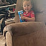 Theodore joined the competition — help win amazing prizes! toddler, child, smiling, curly_hair, red_shirt, blue_container, armchair, brown_furniture, shoes, boots, shelf, indoor, home, cozy, happy, person, seated, natural_light, casual, portrait