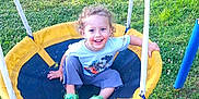 Theodore joined the competition — help win amazing prizes! child, toddler, swing, playground, grass, outdoor, smiling, happy, curly_hair, green_shoes, casual_clothing, yellow_swing, blue_pants, daylight, fun, recreation, park, person, sitting, play