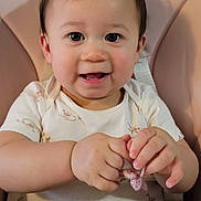Ashlee joined the competition — help win amazing prizes! baby, child, high_chair, cute, smiling, hair_tie, crocheted, onesie, pastel_colors, toy, infant, happy, portrait, hands, face, indoor, seat, pink, clothing, person
