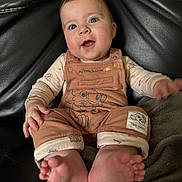 Neo participe au concours pour gagner de l'argent avec cette photo : baby, child, smiling, blue_eyes, overalls, lion_king, simba, foot, hand, couch, blanket, clothing, infant, happy, portrait, indoor, cute, young_child, sitting, closeup