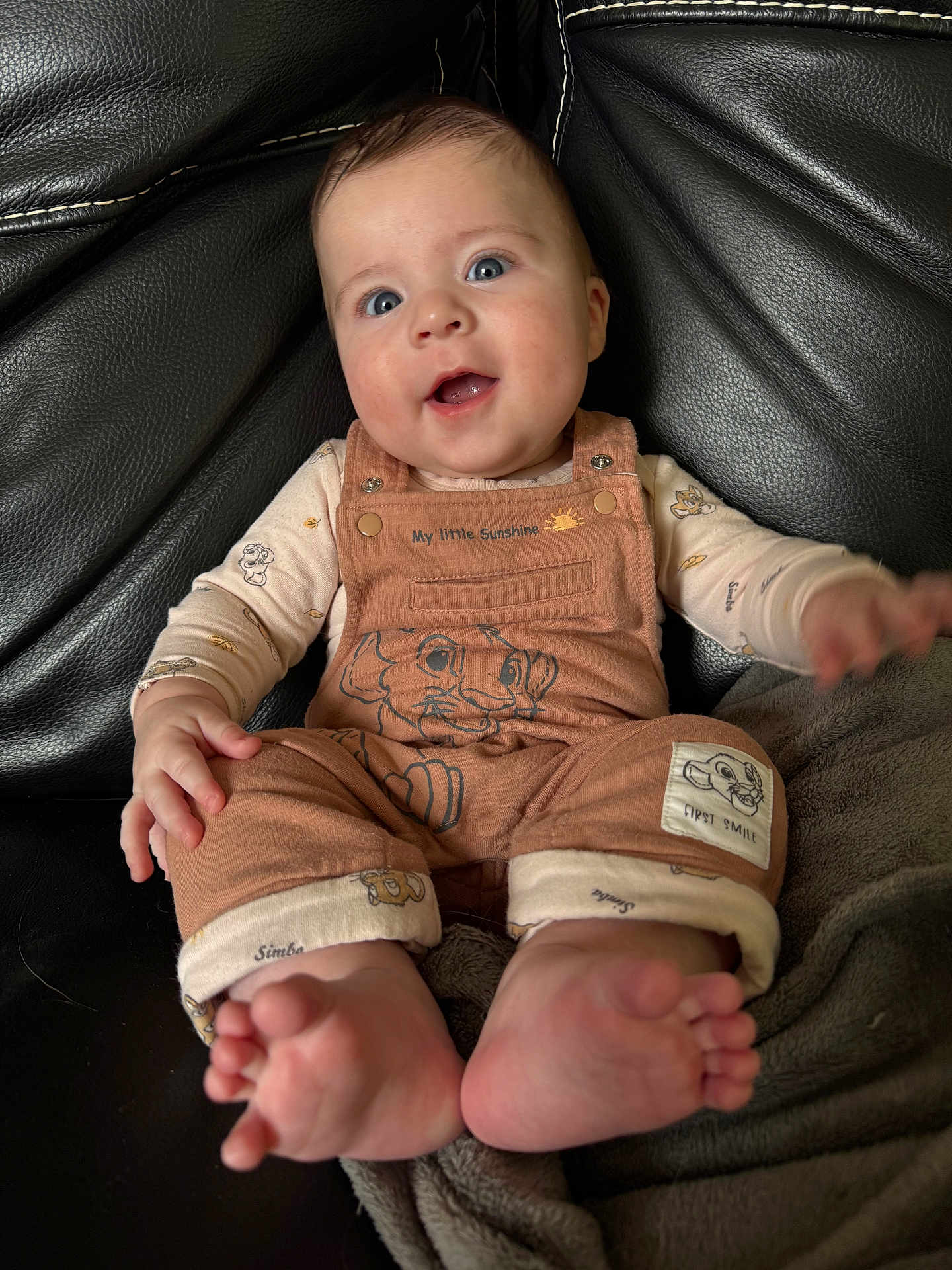 Neo participe au concours pour gagner de l'argent avec cette photo : baby, child, smiling, blue_eyes, overalls, lion_king, simba, foot, hand, couch, blanket, clothing, infant, happy, portrait, indoor, cute, young_child, sitting, closeup