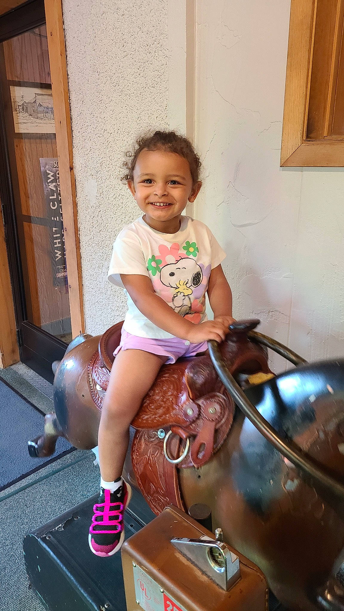 Izzy joined the competition — help win amazing prizes! bridle, child, event, facial_expression, fun, happy, horse, horse_tack, human_leg, joy, knee, leisure, person, pink, recreation, shorts, sitting, smile, thigh, toddler