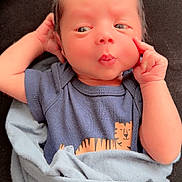 Micheal joined the competition — help win amazing prizes! baby, infant, newborn, blanket, blue_clothing, tiger_print, face, hand, puckered_lips, cute, wrapped, resting, portrait, indoors, soft_texture, child, person, skin, expression, lying_down