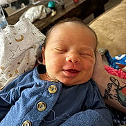 Aiden joined the competition — help win amazing prizes! newborn, baby, smiling, sleeping, blue_outfit, buttons, hand, tattoo, blanket, couch, living_room, face, infant, comfort, resting, portrait, closeup, person, cozy, indoors