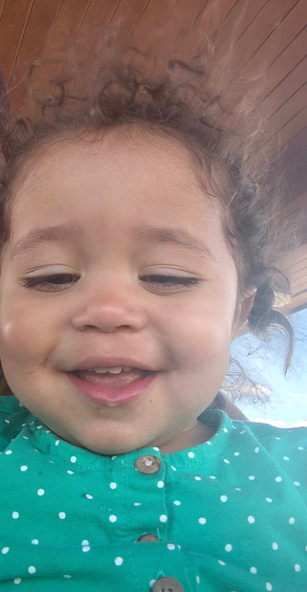 Xariah is registered to the contest to win money with this photo: toddler, child, smile, face, curly_hair, green_shirt, polka_dot, buttoned_shirt, close_up, selfie, indoors, wooden_ceiling, sky, happy, young_child, portrait, cute, casual_clothing, daylight, natural_light