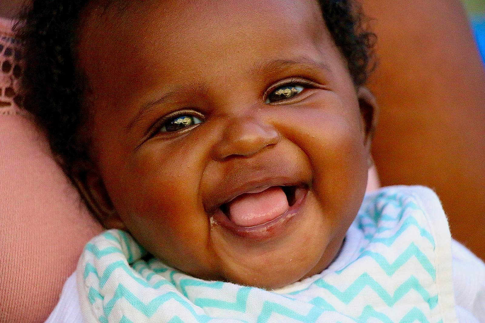 Raëlynn a rejoint le concours — aidez-le/la à gagner de superbes lots ! baby, smile, face, closeup, child, infant, joy, happy, mouth, tongue, bib, clothing, skin, eyes, chevron_pattern, expression, cute, portrait, person, young