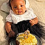 baby, child, birthday_cake, candle, flower_headband, white_top, black_skirt, plate, cake, icing, sprinkles, hand, fingers, blanket, soft_texture, celebration, portrait, indoor, cute, person