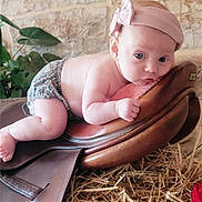 Capucine participe au concours pour gagner de l'argent avec cette photo : baby, headband, leather, saddle, straw, stone_wall, plant, indoor, curious, child, diaper, pink, face, skin, resting, closeup, person, infant, cute, portrait