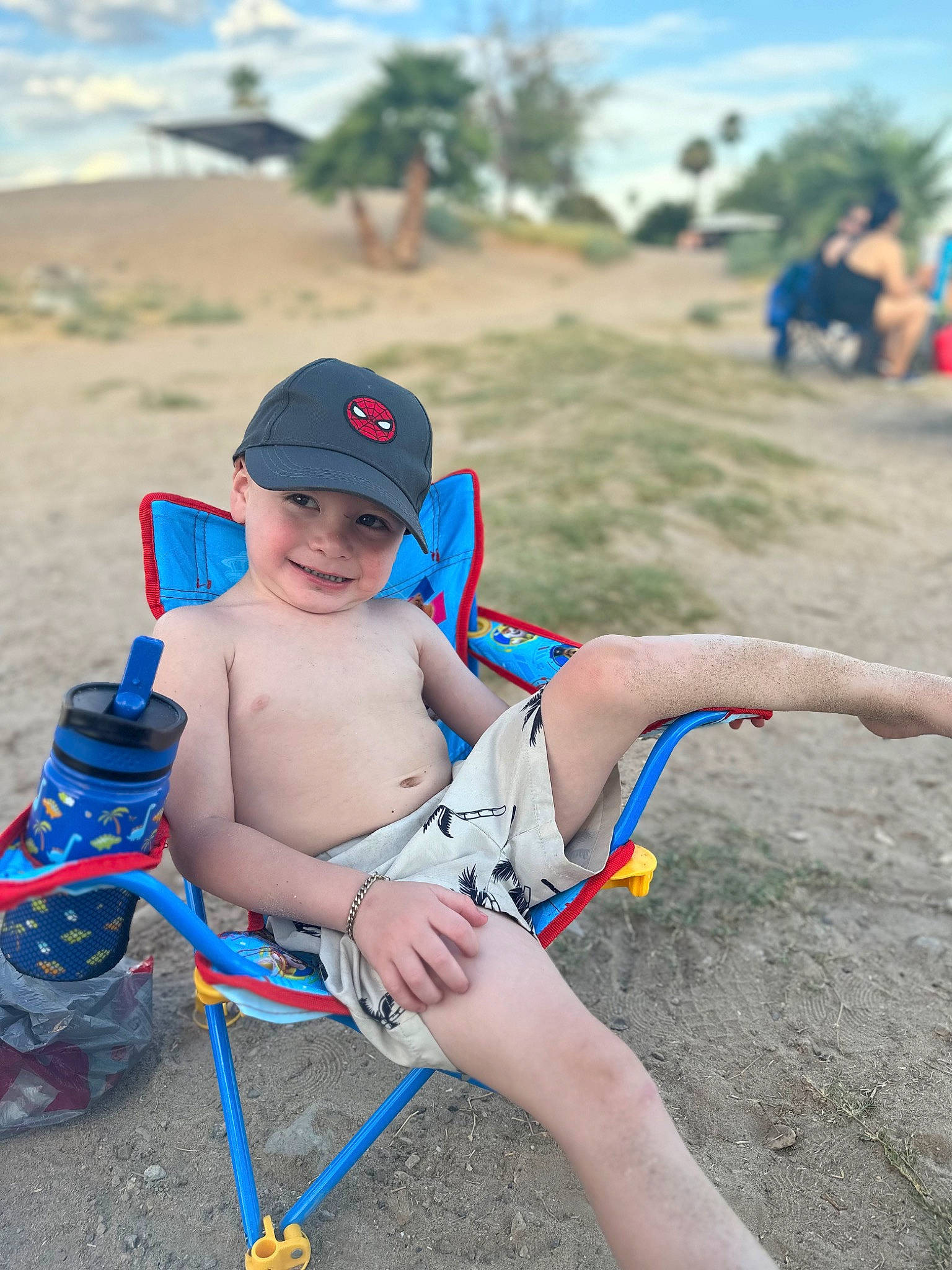Gabriel is registered to the contest to win money with this photo: beach, electric_blue, fun, happy, hat, headwear, joy, knee, landscape, leg, leisure, person, plant, recreation, sand, shorts, sitting, sky, smile, thigh