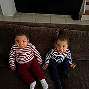 Ulysse a rejoint le concours — aidez-le/la à gagner de superbes lots ! child, toddler, striped_shirt, red_pants, navy_pants, socks, couch, living_room, curly_hair, brown_couch, indoor, floor_tiles, stairs, pillows, two_children, cute, seated, looking_up, home, casual_clothing