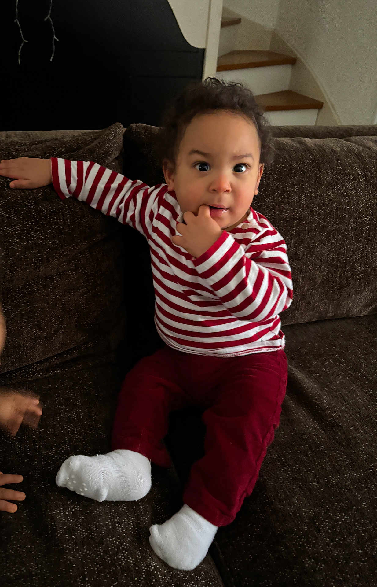 Ulysse participe au concours pour gagner de l'argent avec cette photo : toddler, child, striped_shirt, red_pants, white_socks, couch, indoor, curly_hair, hand_on_couch, finger_in_mouth, staircase, brown_furniture, expression, portrait, sitting, young_child, casual_clothing, home_interior, curious, face