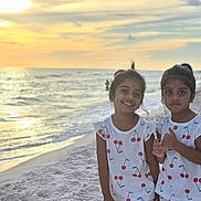 Aarvi Patel is registered to the contest to win money with this photo: beach, cherry_pattern, children, dresses, family, girls, matching_outfits, ocean, outdoor, portrait, sand, seaside, shoreline, siblings, smiling, sunlight, sunset, thumbs_up, vacation, waves