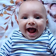 Romain participe au concours pour gagner de l'argent avec cette photo : baby, smiling, striped_shirt, blue_and_white, infant, happy, face, portrait, lying_down, blanket, floral_pattern, cute, child, young, skin, eyes, mouth, clothing, indoors, person