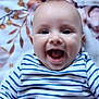 baby, smiling, striped_shirt, blue_and_white, infant, happy, face, portrait, lying_down, blanket, floral_pattern, cute, child, young, skin, eyes, mouth, clothing, indoors, person