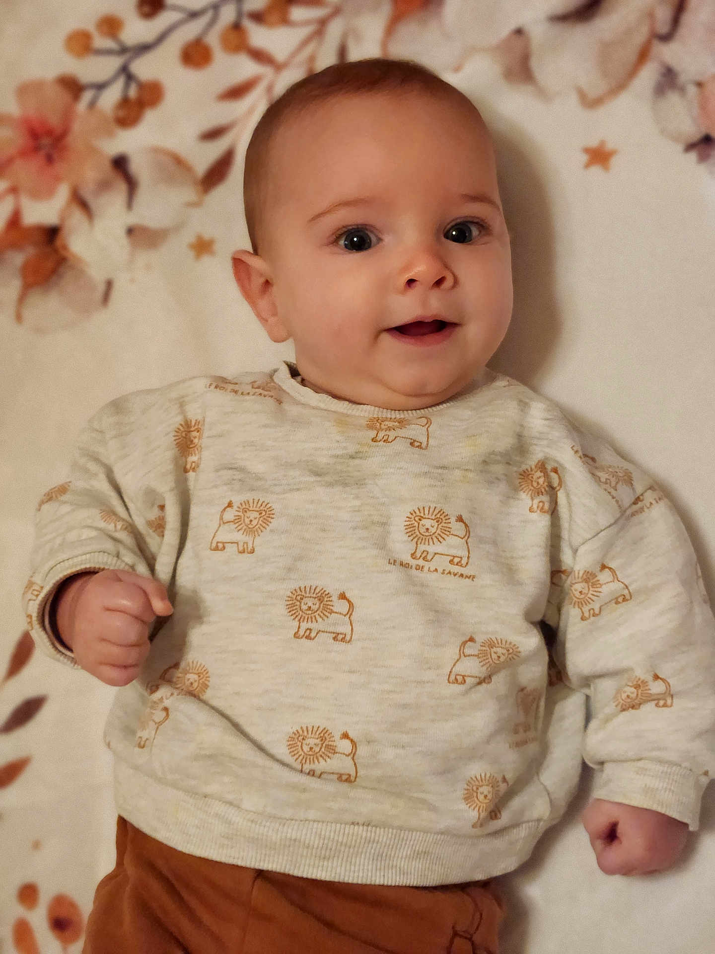 Romain a rejoint le concours — aidez-le/la à gagner de superbes lots ! baby, child, infant, smiling, face, sweater, lion_pattern, clothing, hand, portrait, lying_down, blanket, floral, cute, happy, indoors, skin, head, eyes, person