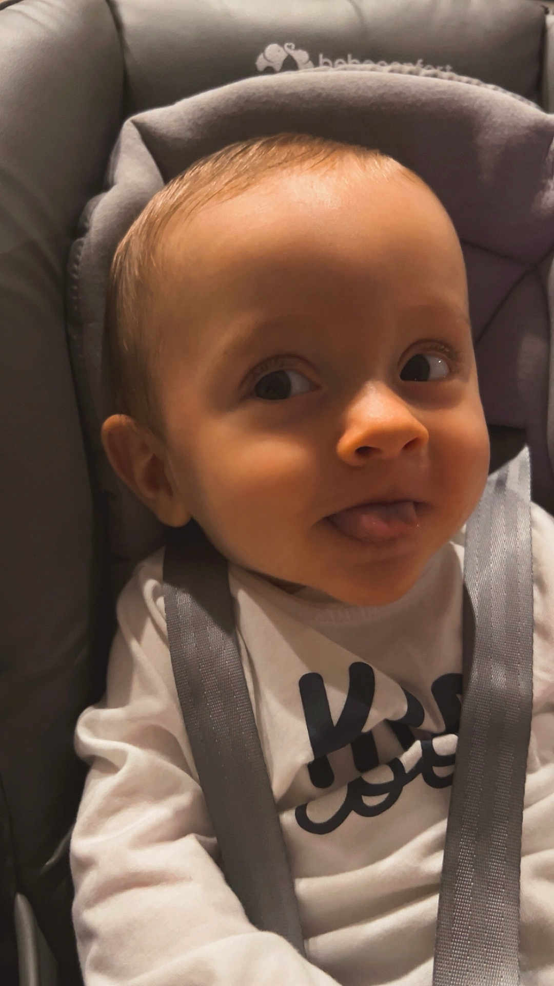 Lilio Mocrette participe au concours pour gagner de l'argent avec cette photo : baby, child, car_seat, tongue_out, curious, straps, clothing, white_shirt, indoor, seat, face, young_child, infant, cute, expression, person, head, smile, closeup, playful